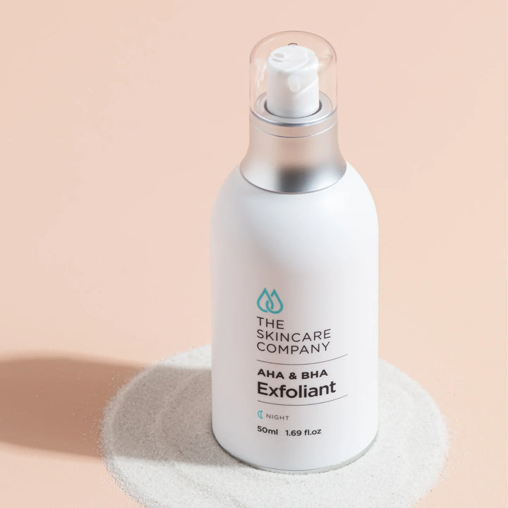 AHA BHA exfoliant serum bottle on light pink background with sand circle, 50ml skincare product